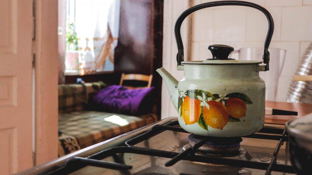 a kettle with art of lemons on it sitting on a hob reinforcing the use of lemons to clean limescale on showerheads and limescale on kettles