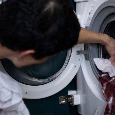 a man loading a washing machine, filling it to capacity to save energy